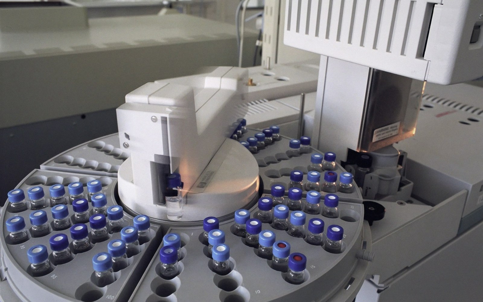 Automated sampler arm selecting capped vials on a rotating carousel tray