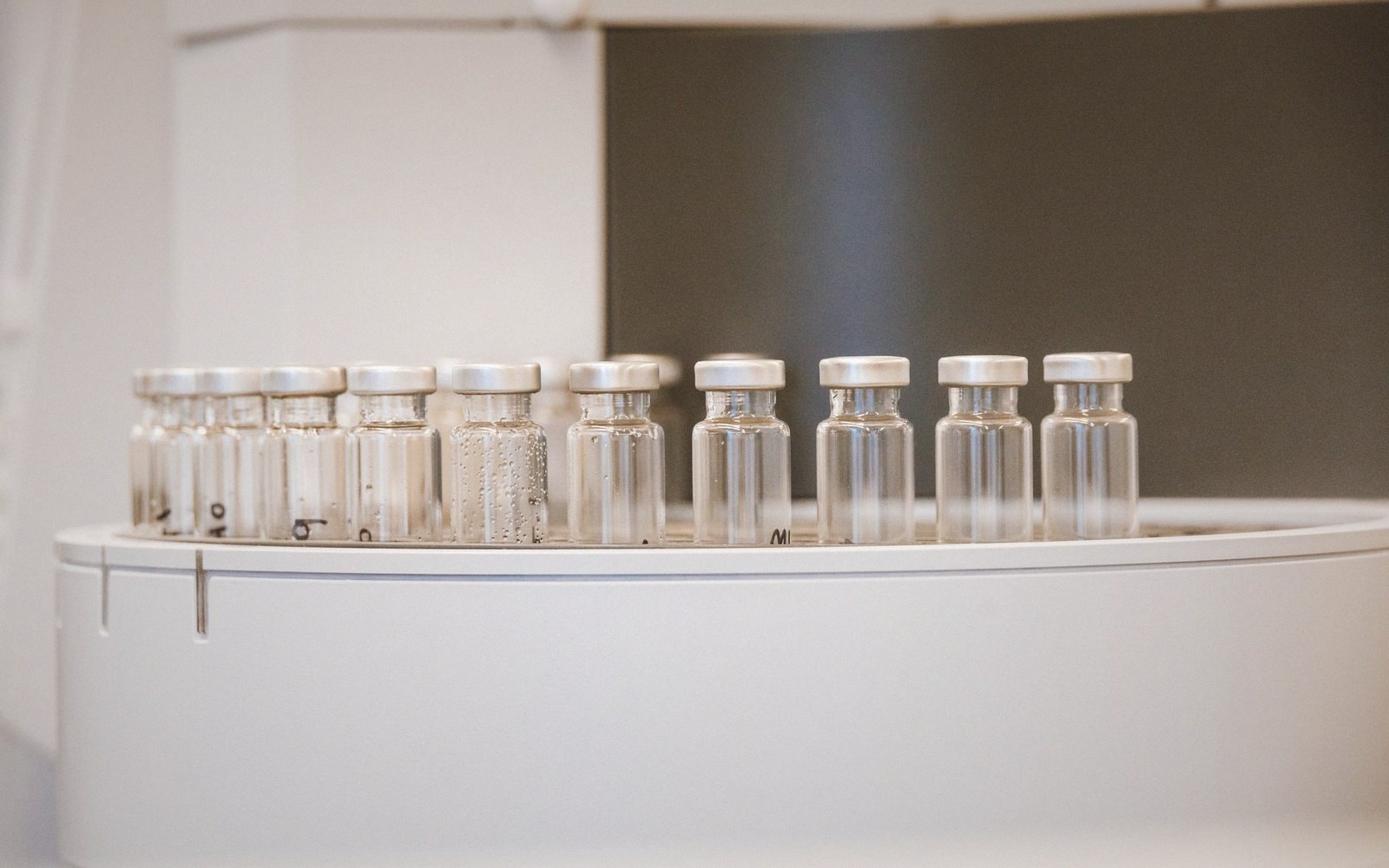 Row of sealed glass vials with metal caps lined up on a lab counter